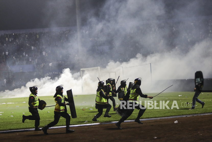  Petugas polisi berlari ketika mereka mencoba untuk menghentikan penggemar sepak bola memasuki lapangan selama bentrokan antara penggemar di Stadion Kanjuruhan di Malang, Jawa Timur, 01 Oktober 2022. Sedikitnya 127 orang termasuk petugas polisi tewas sebagian besar karena terinjak-injak setelah bentrokan antara penggemar dari dua tim sepak bola Indonesia,