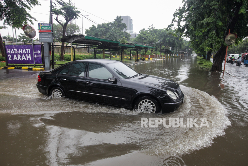 Mobil melewati genangan air di Jalan Letjen Suprapto, Cempaka Putih, Jakarta, Kamis (29/2/2024). Hujan deras yang mengguyur Jakarta sejak dini hari dan buruknya drainase membuat ruas jalur lambat pada jalan tersebut tergenang air.