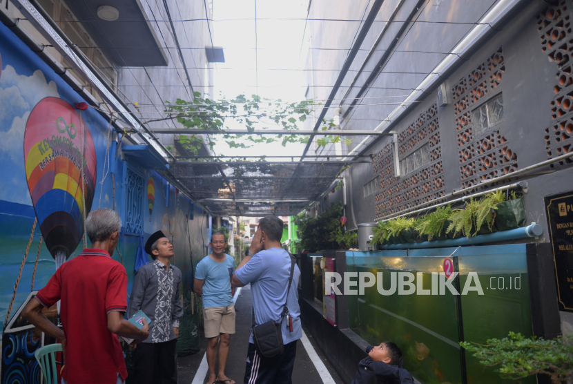 Warga berbincang di dekat kolam gizi di Pusat Percontohan Pencegahan Krisis Planet di Gang Padat Penduduk Jalan Nusa Indah IV Gang 8 RT 8/RW 4 , Malaka Jaya, Jakarta, Jumat (10/5/2024). Pusat percontohan pencegahan krisis planet di gang padat penduduk ini  merupakan sebuah inovasi untuk mengedukasi warga sekaligus bentuk kepedulian akan kelestarian lingkungan sebagai upaya mencegah terjadinya planetary crisis atau perubahan iklim.