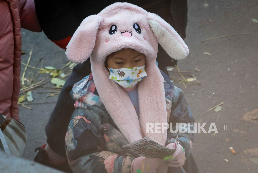 Seorang anak memakai masker setelah pulang dari sekolah di Beijing, Cina, 23 November 2023. 