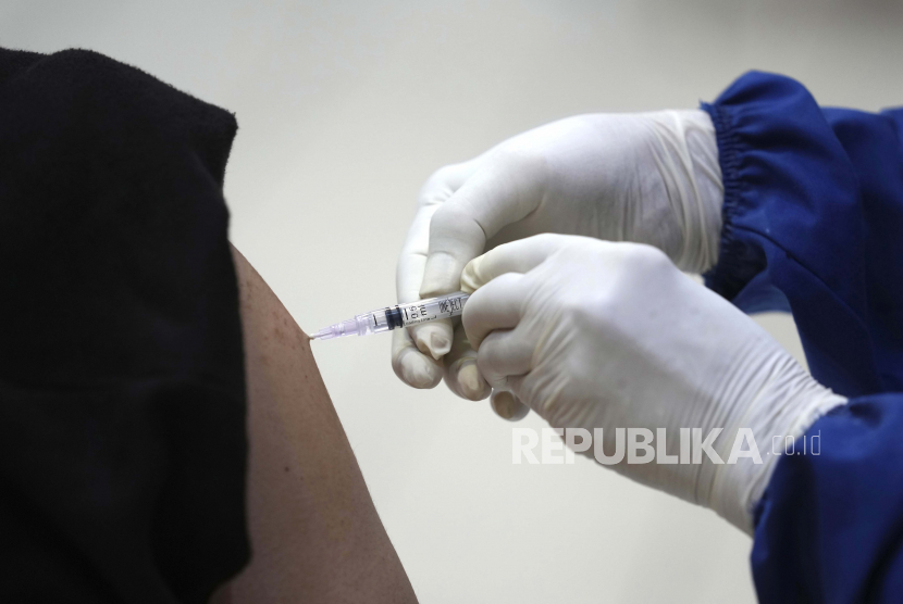 Seorang pekerja medis memberikan suntikan vaksin AstraZeneca.