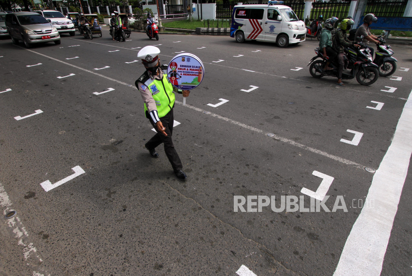 Polisi mengatur pengendara sepeda motor untuk berhenti di belakang garis untuk menjaga jarak antarpengendara saat sosialisasi penerapan jaga jarak di Kota Lhokseumawe, Aceh, Rabu (15/7/2020). Garis tersebut dibuat untuk membatasi jarak antarpengendara di kawasan traffic light guna mencegah penyebaran COVID-19. 