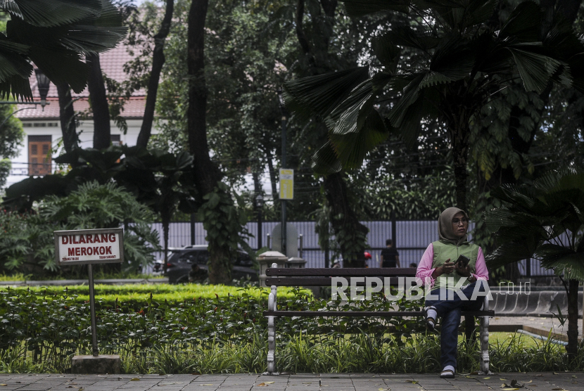 Warga duduk di bangku saat mengunjungi Taman Suropati, Kecamatan Menteng, Jakarta Pusat, Jumat (18/3/2022). 