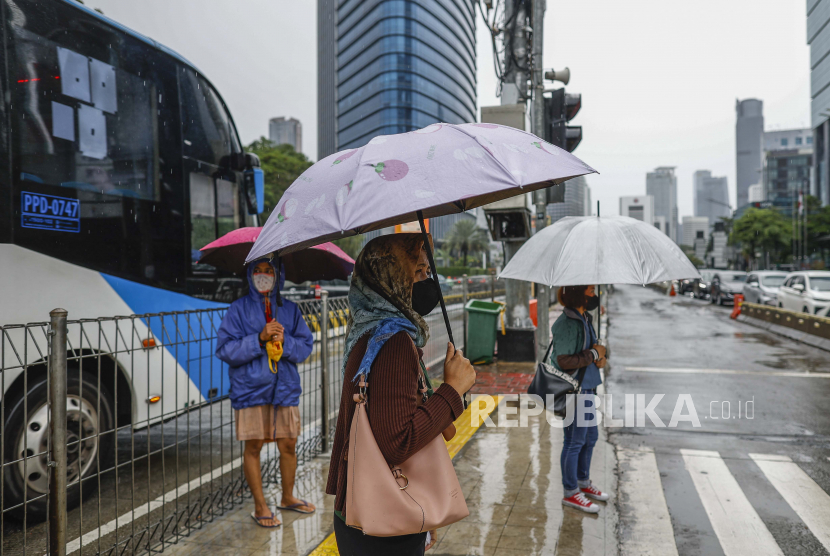 Orang-orang memegang payung di bawah hujan, melintasi jalan yang sibuk di Jakarta. Badan Meteorologi, Klimatologi, dan Geofisika (BMKG) Indonesia telah mengeluarkan peringatan publik untuk cuaca ekstrem (ilustrasi).