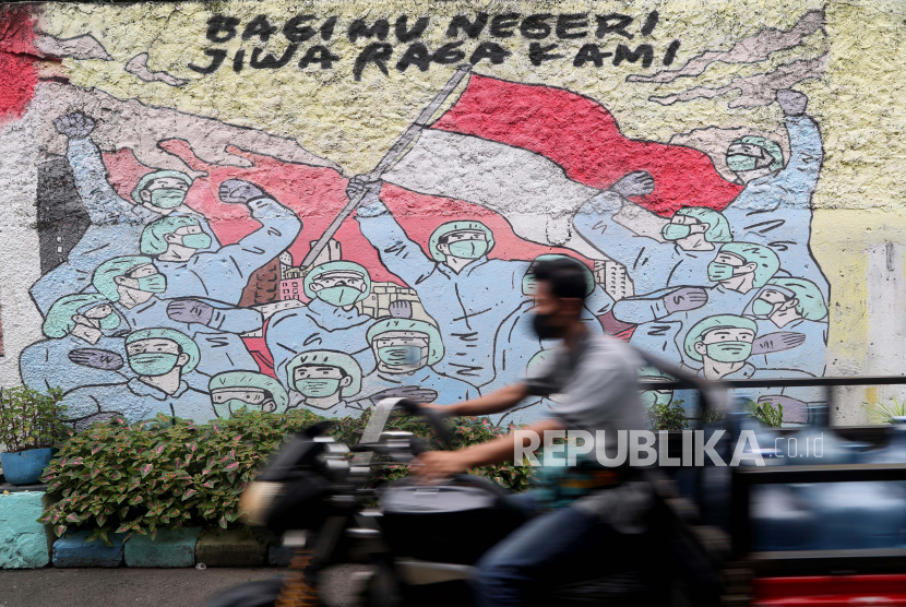  Seorang pria mengendarai sepeda motornya melewati mural kampanye Covid-19 di Tanggerang, Banten.  Presiden Joko Widodo (Jokowi) menekankan percepatan vaksinasi dan menerapkan protokol kesehatan secara ketat adalah kunci utama dalam mengendalikan pandemi Covid-19. 