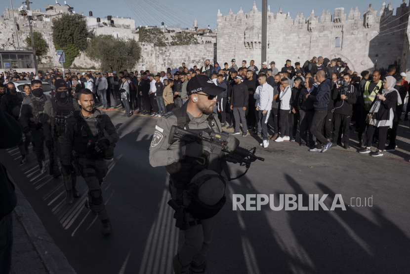 Warga Palestina melihat saat pasukan keamanan Israel berpatroli di dekat Gerbang Damaskus, tepat di luar Kota Tua Yerusalem, Rabu, 20 April 2022. 