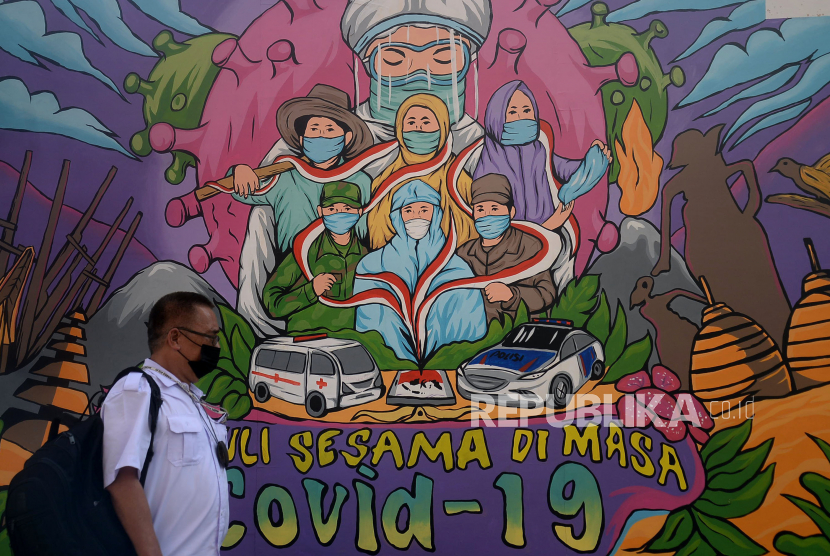 Pejalan kaki melintas didekat mural bertema covid-19 dikawasan Lapangan Bhayangkara, Jakarta. Jumlah suntikan harian Covid-19 ini tercatat mengalami penurunan selama empat pekan terakhir.