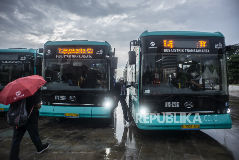 Petugas berjalan di dekat Bus Listrik Transjakarta di Plaza Monas, Jakarta, Selasa (8/3/2022). Perusahaan bus PT Mayasari Bakti segera menambah sebanyak 22 unit bus listrik untuk operasional Transjakarta pada 2023 mendatang.