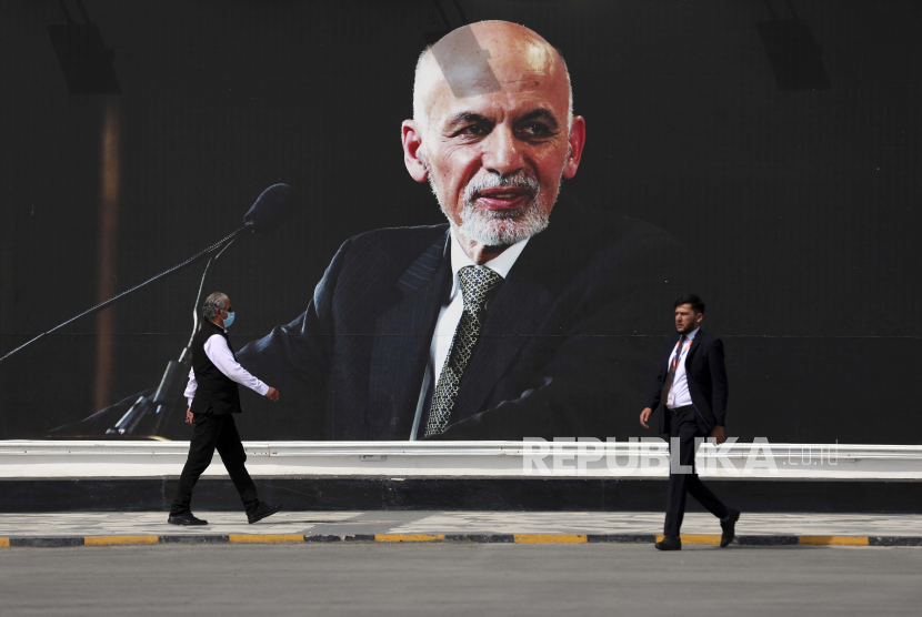  Orang-orang berjalan di dekat lukisan dinding Presiden Ashraf Ghani di Bandara Internasional Hamid Karzai, di Kabul, Afghanistan, Sabtu, 14 Agustus 2021.