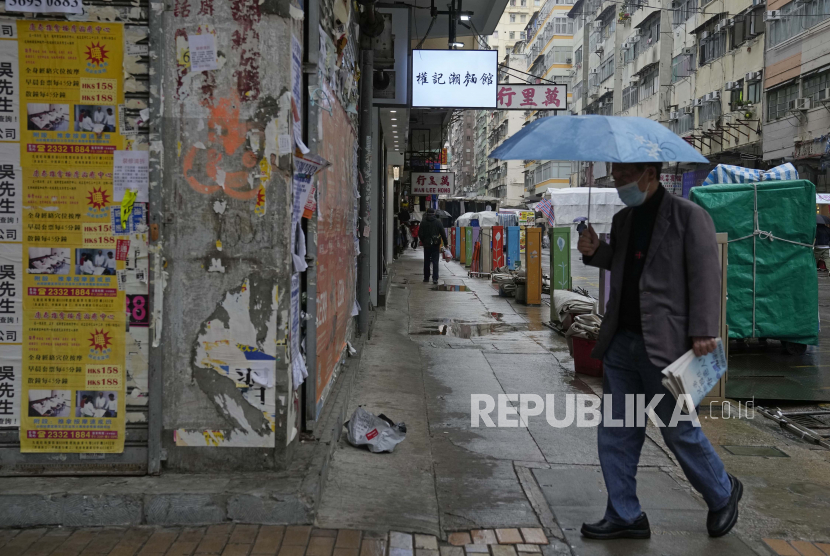 Seorang pria yang mengenakan masker, berjalan di jalan di Hong Kong.