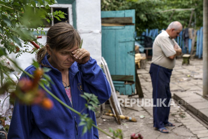 Nina Bilyk, kiri, menyeka air mata Sabtu, 13 Agustus 2022, sambil berdiri di mana pasangannya, Ivan Fartukh, sepupu Andrii Fartukh, kanan, tewas dalam serangan roket Rusia tadi malam di rumah mereka di Kramatorsk, wilayah Donetsk , Ukraina timur. Serangan itu menewaskan tiga orang dan melukai 13 lainnya, menurut walikota. Serangan itu terjadi kurang dari sehari setelah 11 roket lainnya ditembakkan ke kota itu.