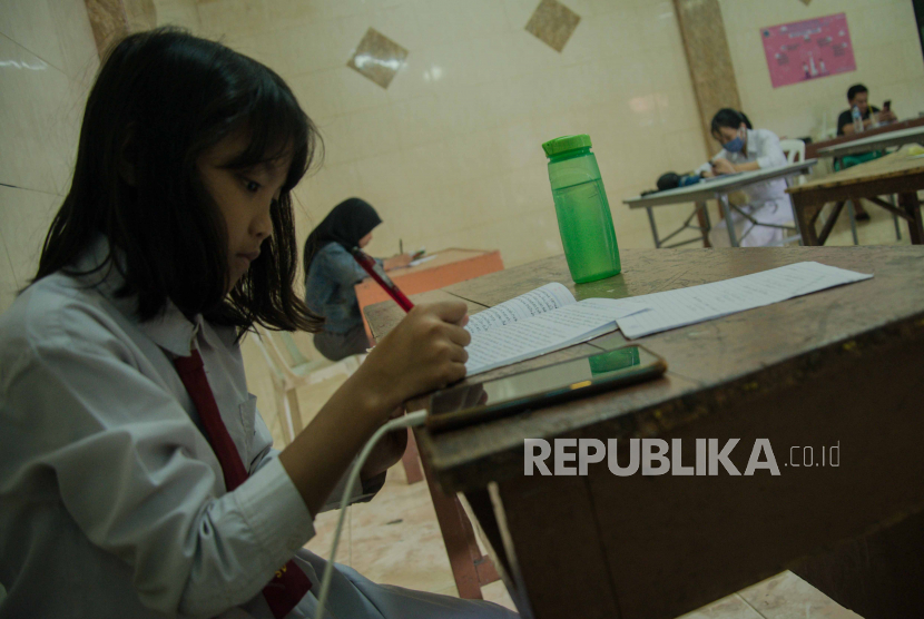 Siswa mengerjakan soal penilaian akhir semester (PAS) tahun ajaran 2020/2021 menggunakan layanan Jakwifi di posyandu kawasan Kelurahan Galur, Jakarta, Senin (30/11). Ujian penilaian akhir semester (PAS) tahun ajaran 2020/2021 hari ini mulai dilaksanakan hingga 10 Desember mendatang di sejumlah sekolah di Jakarta dengan metode pengerjaan dilakukan di rumah secara daring. Republika/Thoudy Badai
