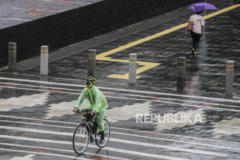 Pesepeda memakai jas hujan saat hujan turun di Jalan Jenderal Sudirman, Jakarta Selatan, Jumat (19/1/2024). 
