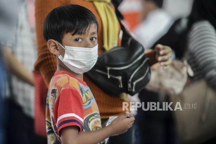 Seorang anak memakai masker saat menunggu kereta di Stasiun Depok, Depok, Jawa Barat, Jumat (6/3).