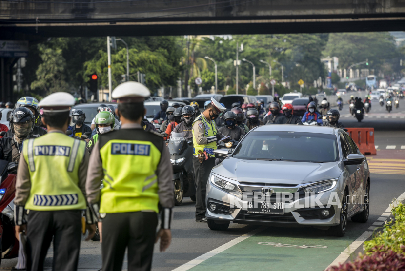 Anggota kepolisian saat menilang pengendara mobil dengan nomor plat ganjil di kawasan Fatmawati, Jakarta.