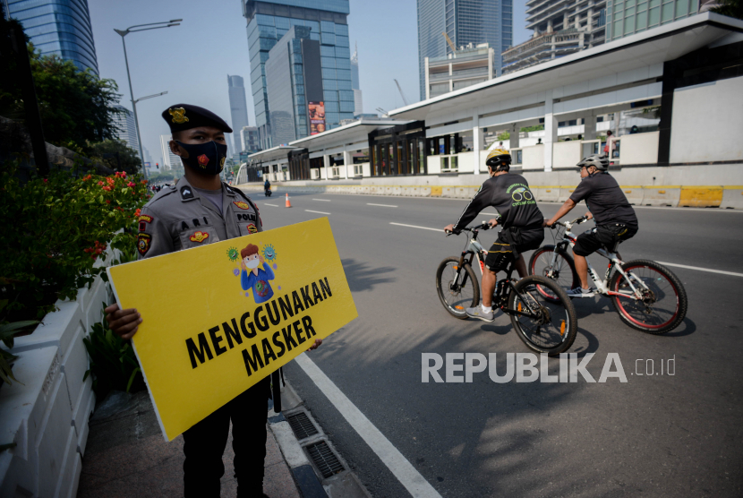 Polisi memegang alat peraga kampanye protokol kesehatan di kawasan Bundaran Hotel Indonesia, Jakarta, Ahad (6/9). Angka positif Covid-19 di DKI Jakarta selama sepekan terakhir mencapai 13 persen, angka tersebut melampaui ambang batas Organisasi Kesehatan Dunia (WHO) yakni dibawah 5 persen.