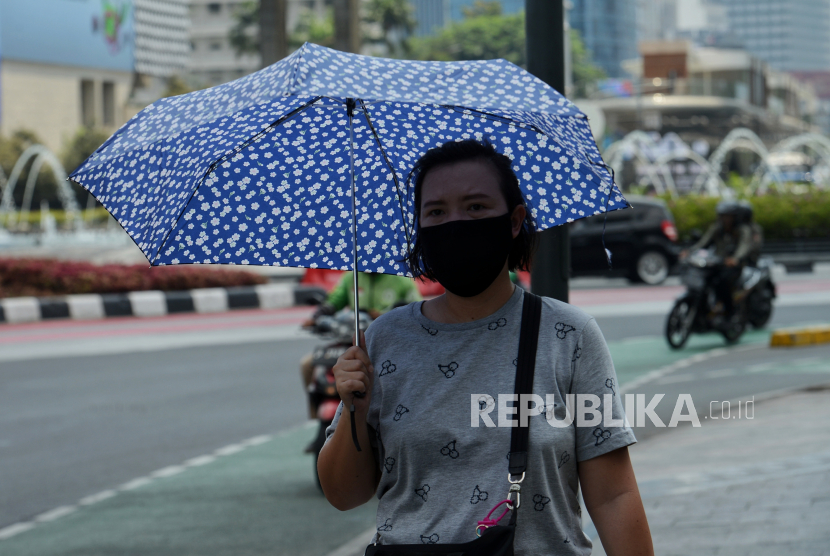 Perkeja melindungi tubuh dari terik matahari menggunakan payung saat berjalan di kawasan Sudirman, Jakarta, Senin (18/12/2023). Cegah heat stroke saat cuaca sedang panas terik.