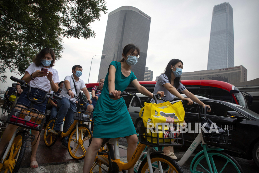 Orang-orang yang memakai masker wajah untuk melindungi dari virus corona menunggu di persimpangan di kawasan pusat bisnis di Beijing, Jumat, 31 Juli 2020. China melaporkan adanya sembilan kasus impor Covid-19 pada Sabtu (29/8).