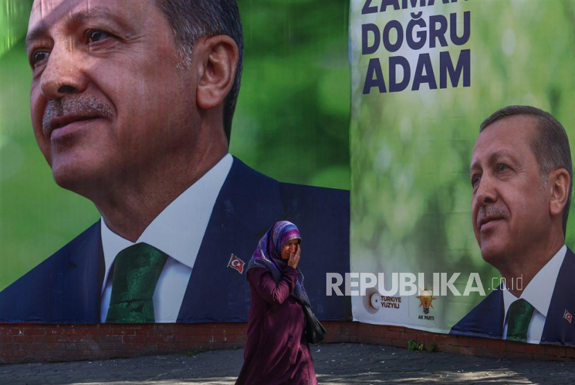 Seorang pria berjalan di depan foto Presiden Turki Recep Tayyip Erdogan di Istanbul, Turki, 24 April 2023. Pemilihan umum akan diadakan di Turki pada 14 Juni 2023 dengan pemungutan suara dua putaran untuk memilih Presiden Turki dan pemilihan parlemen secara bersamaan untuk memilih anggota Majelis Nasional Agung Turki.