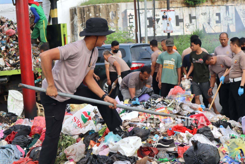 Ratusan personel Polresta Cirebon bergotong royong bersama warga membersihkan sampah yang menumpuk di jalan sekitar terowongan kereta api di Desa Mertapada Wetan, Kecamatan Astanajapura, Kabupaten Cirebon, Kamis (13/7/2023). 
