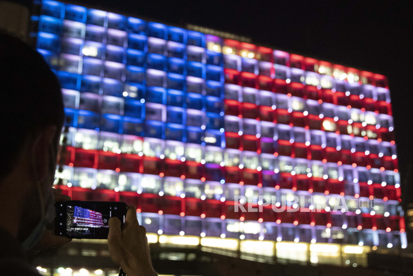  Seorang pria Israel mengambil gambar gedung kotamadya Tel Aviv yang diterangi dengan bendera Amerika Serikat di Tel Aviv, Israel, Kamis, 7 Januari 2021.