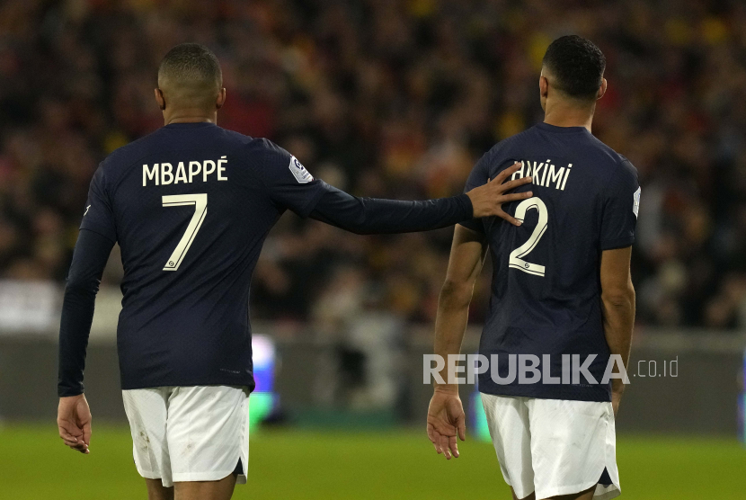 Striker Paris Saint-Germain (PSG) Kylian Mbappe menepuk punggung rekannya, Achraf Hakimi (kanan) selama pertandingan sepak bola Ligue 1 Prancis antara Lens dan PSG di Stadion Bollaert di Lens, Prancis, Senin (9/1/2023) dini hari WIB. 
