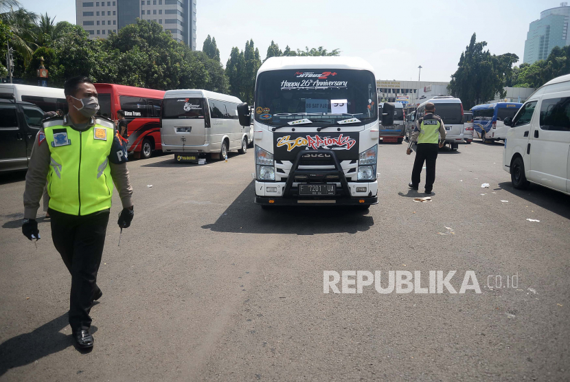 Seorang polisi melintas di depan mobil travel gelap yang terjaring dalam operasi khusus di titk penyekatan di Polda Metro Jaya, Jakarta, Senin (11/5). Dalam kurun waktu tiga hari operasi khusus tersebut, yakni mulai 8-10 Mei, Polda Metro Jaya mengamankan 202 kendaraan travel gelap yang mencoba mengangkut pemudik ke luar dari Jakarta