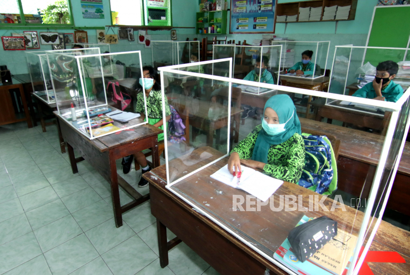 Murid mengikuti sekolah tatap muka di kelas yang dilengkapi dengan bilik plastik di SDN 1 Lateng, Banyuwangi, Jawa Timur.