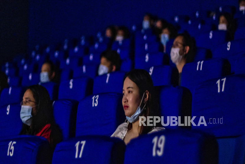  Orang-orang memakai masker wajah dan duduk berjarak ketika menonton film di sebuah bioskop di Shanghai, China, 20 Juli 2020. 