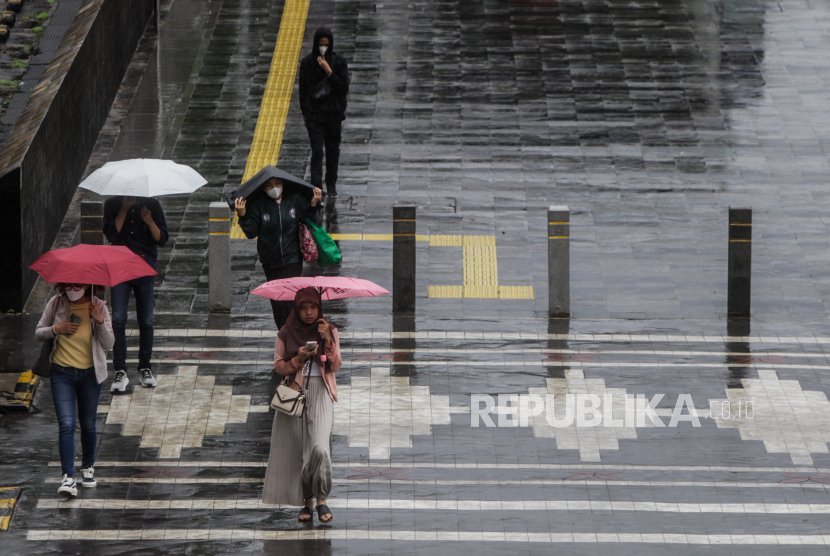 Warga memakai payung saat hujan turun di Jalan Jenderal Sudirman, Jakarta Selatan, Jumat (19/1/2024). BMKG menyebut curah hujan masih tinggi karena MJO dan Rossby Ekuator.