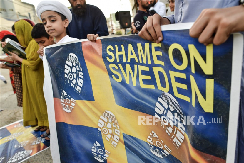 Demonstran memamerkan dan menginjak bendera Swedia tiruan saat protes terhadap pembakaran salinan Alquran di Swedia, di Karachi, Pakistan. 