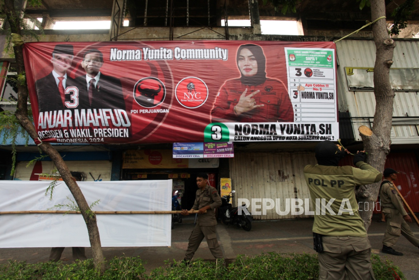 Petugas membongkar alat peraga kampanye (APK) di Jalan Urip Sumoharjo, Surabaya, Jawa Timur, Kamis (7/12/2023). Penertiban terhadap sejumlah APK yang terpasang di sejumlah tempat di Surabaya dilakukan karena pemasangan APK dalam masa kampanye tersebut telah melanggar aturan yang telah ditentukan.
