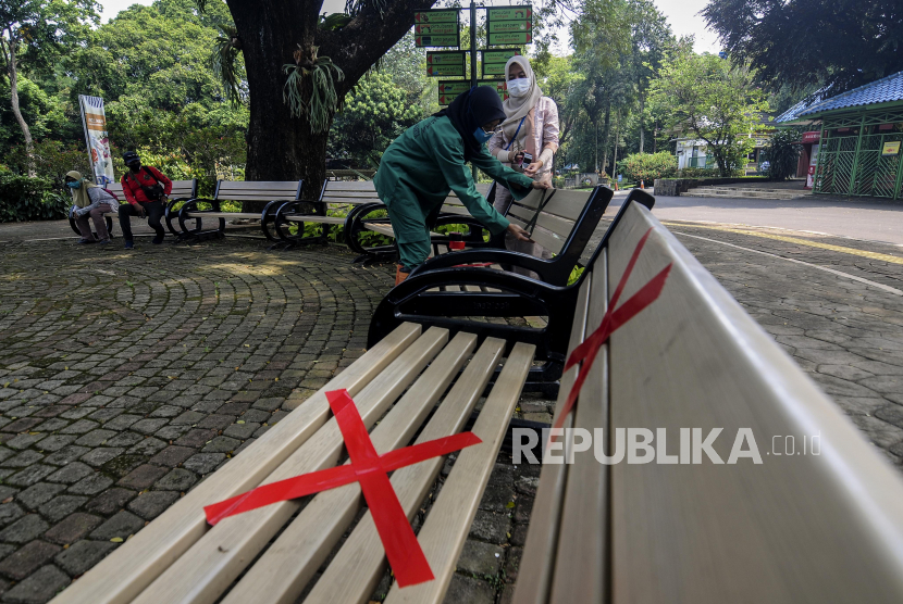 Petugas memasang tanda jarak di bangku saat simulasi persiapan pembukaan kembali Taman Margasatwa Ragunan, Jakarta Selatan, Kamis (11/6). Ragunan dibuka kembali untuk umum pada Sabtu (20/6).