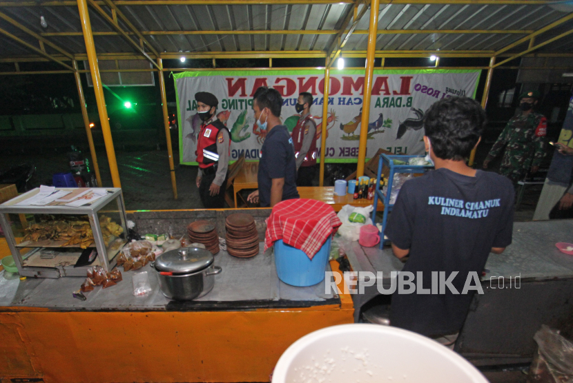 Petugas gabungan menegur pedagang kaki lima yang melanggar jam operasional hingga pukul 20.00 WIB saat melakukan patroli di Indramayu, Jawa Barat, Minggu (4/7/2021) malam. Petugas gabungan melakukan patroli di berbagai titik untuk mengawasi dan memastikan penerapan aturan PPKM Darurat guna menekan angka penyebaran kasus COVID-19. 