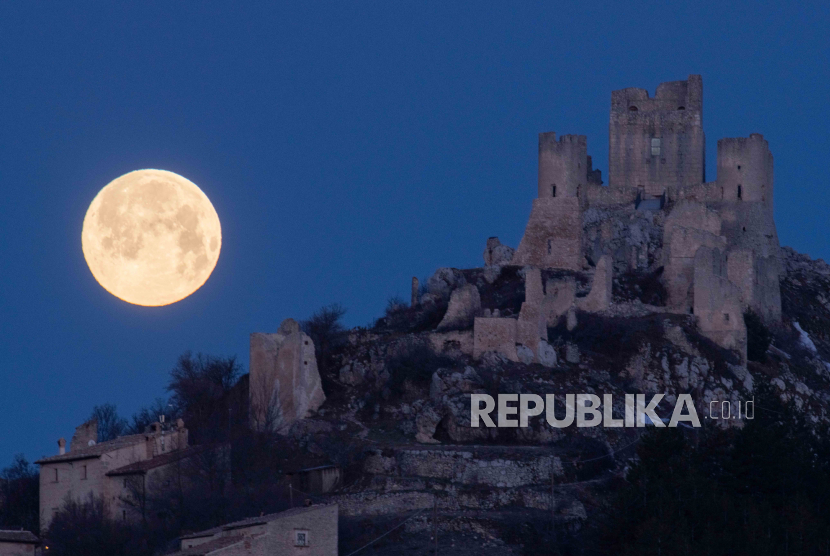 Bulan purnama terbenam di belakang kastil dan desa Rocca Calascio (L Aquila), Italia, Selasa (7/3/2023). Malaikat Datang Saat Subuh dan Ashar