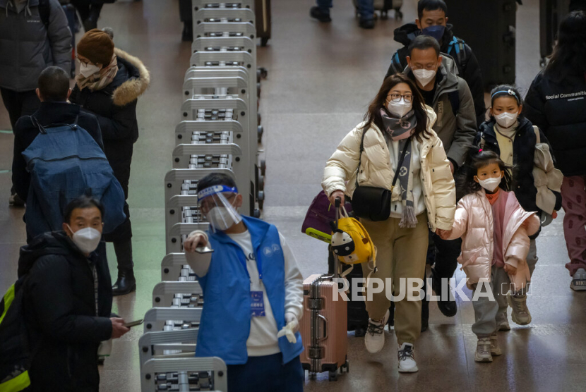  Sebuah keluarga membawa barang bawaan mereka berjalan di sepanjang concourse di Stasiun Kereta Api Beijing West di Beijing, China, Rabu (18/1/2023). Populasi yang telah mencapai puncak dan perlahan menyusut akan menimbulkan tantangan baru bagi para pemimpin China.