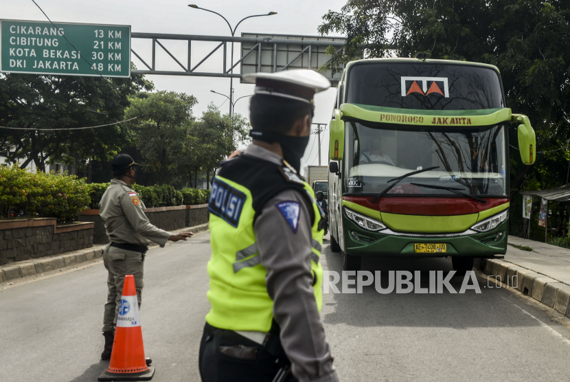 Polisi menghentikan bus saat penerapan pelarangan mudik di Jalur Pantura, Perbatasan Kabupaten Bekasi dengan Karawang, Kabupaten Bekasi, Jawa Barat, Sabtu (25/4). Hari kedua penerapan pelarangan mudik di jalur pantura masih banyak pengendara yang memaksakan untuk mudik dan tidak menerapkan jarak sosial