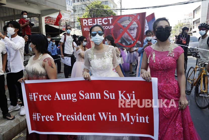  Wanita mengenakan gaun pesta memegang spanduk saat mereka berbaris selama protes menentang kudeta militer, di Yangon, Myanmar, 10 Februari 2021. Orang-orang terus berdemonstrasi di seluruh negeri meskipun ada perintah yang melarang pertemuan massal dan laporan peningkatan penggunaan kekuatan oleh polisi terhadap pengunjuk rasa anti-kudeta. 