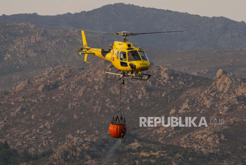  Sebuah helikopter mengangkut air selama pemadaman kebakaran hutan bekerja di dekat Becerril de la Sierra, di pinggiran Madrid, Selasa, 12 Juli 2022. Gelombang panas, yang kedua untuk Spanyol dalam waktu kurang dari sebulan dan yang pertama tahun ini untuk Portugal, diperkirakan akan terjadi. berlangsung setidaknya sampai akhir pekan, kata para pejabat Selasa. Suhu yang sudah tinggi terus meningkat, meningkatkan kekhawatiran akan memicu kebakaran hutan yang lebih tidak terkendali