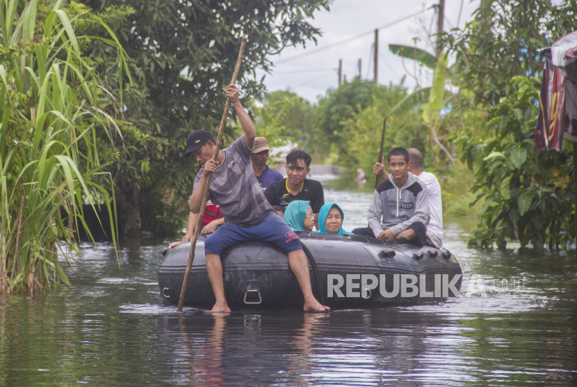 Relawan menggunakan perahu karet  mengevakuasi warga yang terdampak banjir di Desa Banua Raya, Kabupaten Tanah Laut, Kalimantan Selatan, Senin (11/1/2021). Berdasarkan data yang telah di himpun aparat desa Banua Raya, sebanyak 2.907 Jiwa terdampak banjir akibat luapan sungai Bati Bati. 