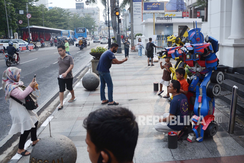 Pengunjung berfoto dengan cosplay tokoh kartun di kawasan alun-alun, Kota Bandung, Ahad (19/7). Mulai ramainya pengunjung di akhir pekan, membuat para cosplayer berbagai tokoh film kembali meramaikan kawasan alun-alun Kota Bandung. Mereka berharap rezeki dari para pengunjung yang berswafoto.  