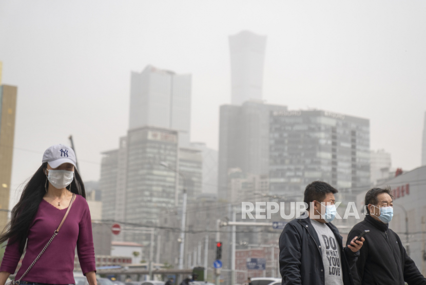  Orang-orang yang memakai masker berjalan melintasi persimpangan saat terjadi badai debu dan pasir di Beijing, 4 April 2023.  