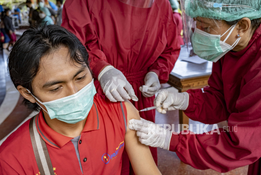 Seorang petugas kesehatan bereaksi saat menerima dosis vaksin COVID-19 di pusat vaksinasi di Denpasar, Bali, Indonesia, 04 Februari 2021.