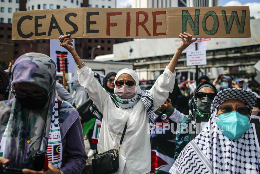 Seorang wanita memegang plakat saat unjuk rasa Bebaskan Palestina di dekat kedutaan AS di Kuala Lumpur, Malaysia, 22 Desember 2023. Puluhan ribu warga Palestina wafat dalam serangan Israel.
