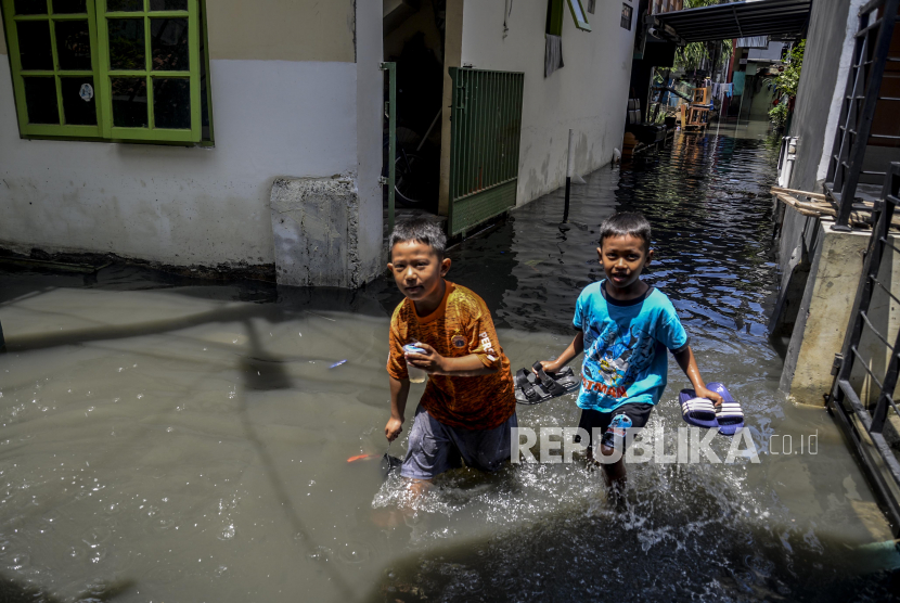 Warga melewati banjir di kawasan Kebon Jeruk, Jakarta