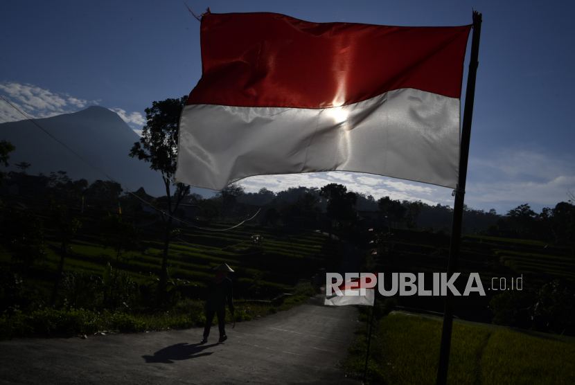 Warga melintas di antara bendera merah putih ketika menuju lokasi upacara peringatan HUT Kemerdekaan ke-76 Republik Indonesia di Taman Refugia, Desa Penanggungan, Trawas, Kabupataen Mojokerto, Jawa Timur, Selasa (17/8/2021). Pemerintah Kabupaten Mojokerto, Jawa Timur, optimistis jika sektor pariwisata diprediksi menjadi salah satu sektor utama yang paling cepat mendongkrak pemulihan ekonomi masyarakat yang lesu akibat pandemi COVID-19. 