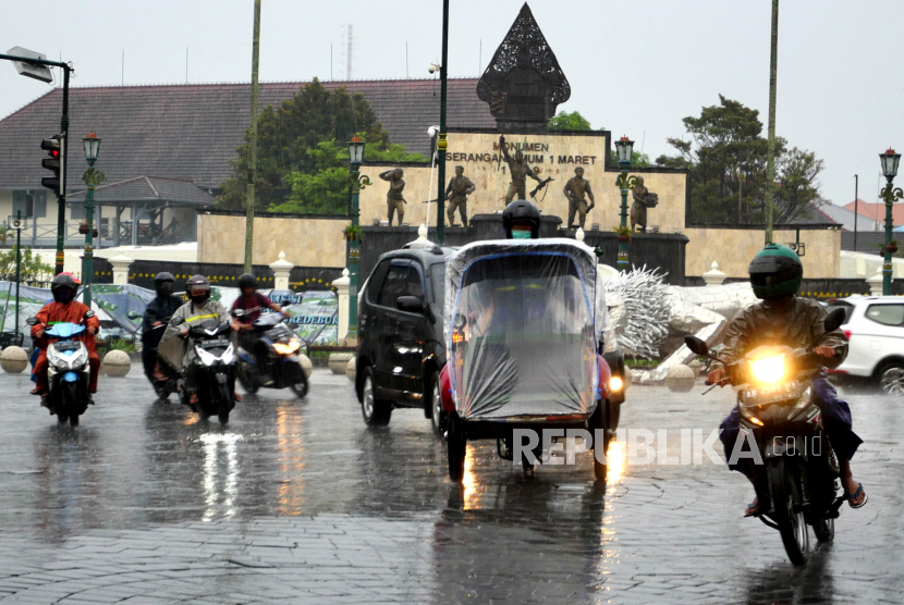 Warga menggunakan ponco menembus hujan di Yogyakarta.