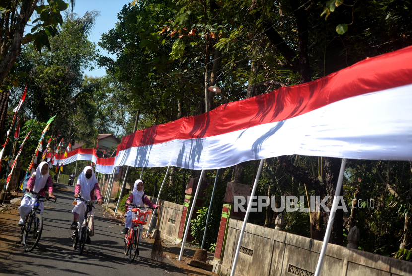  Apa Hukum Mempertahankan Kemerdekaan?  Siswa bersepeda saat pulang sekolah sambil melihat Bendera merah putih yang terpasang di tengah Dusun Karang,, Nanggulan, Kulonprogo, Yogyakarta.