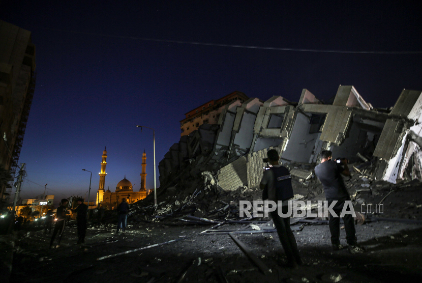 Warga Palestina memeriksa menara Hanadi yang hancur di Kota Gaza, 11 Mei 2021. Setidaknya satu wanita tewas setelah 130 roket yang ditembakkan oleh Hamas dari Jalur Gaza jatuh di Tel Aviv dan kota-kota tetangga Israel.