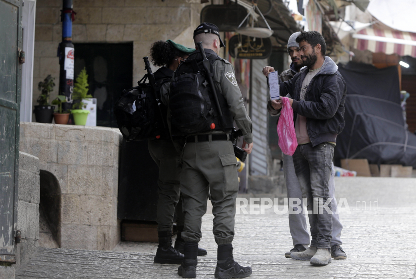Polisi Israel memeriksa surat-surat dari warga Palestina di Kota Tua Jerusalem, untuk membatasi pergerakan dalam mencegah penyebaran virus Corona, Senin (30/3). Kementerian Kesehatan Israel mengumumkan kasus corona telah mencapai 12 ribu lebih. Ilustrasi.